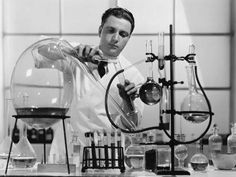 a man in white lab coat pouring liquid into flasks with test tubes and beakles