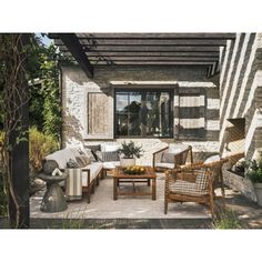 an outdoor living area with wicker furniture and potted plants