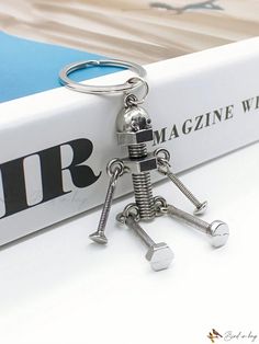 a metal robot keychain sitting on top of a book with two screws attached to it