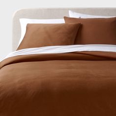 a bed with brown sheets and white pillows