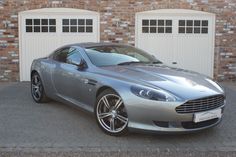 a silver sports car parked in front of two garage doors and brick wall behind it