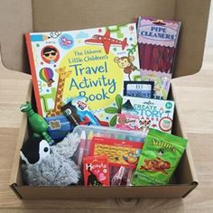 an open cardboard box filled with children's travel activity books, toys and other items