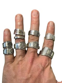 a person's hand with five different rings on it