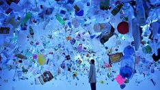 a person standing in front of a large amount of glass bottles and magnets hanging from the ceiling