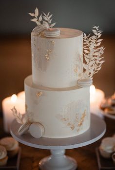 a three tiered wedding cake with white frosting and gold leaves on the top