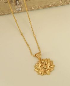 Discover the timeless elegance of the lotus gold plated brass necklace, an exquisite piece that captures the serene beauty of the lotus flower. Each pendant is a crafted representation of a lotus in full bloom, symbolizing purity, enlightenment, and rebirth across various cultures. Artisan-made with care, the necklace features a meticulously designed lotus flower that dangles gracefully from a beaded chain, imbued with a touch of tradition and sophistication. Adjustable length: 16" with an addit Gold Spiritual Flower Necklace, Lotus Gold Pendent, Lotus Locket Gold, Spiritual Gold-plated Flower Pendant Necklace, Spiritual Lotus Flower Necklace Gift, Lotus Flower Pendant, Buddha Groove, Blooming Lotus, Lotus Necklace