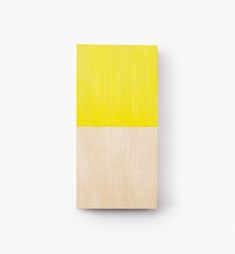 a small wooden block with yellow and white stripes on the front, against a white background