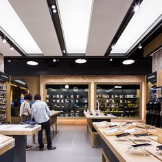 two people are looking at cell phones in a store with shelves full of electronic devices