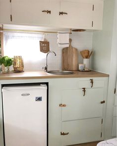 a small kitchen with white cabinets and wooden counter tops, including a dishwasher