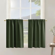 a green curtain hanging in front of a window next to a vase with white flowers