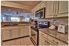 a kitchen with white cabinets and granite counter tops, an oven, microwave, dishwasher and toaster