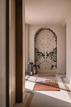 an archway leading into a room with a rug on the floor and two lanterns in front of it