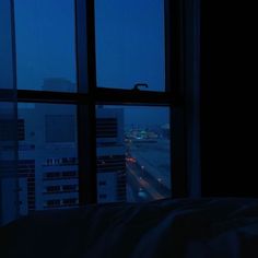 a window view of the city at night from a bed in a room with large windows