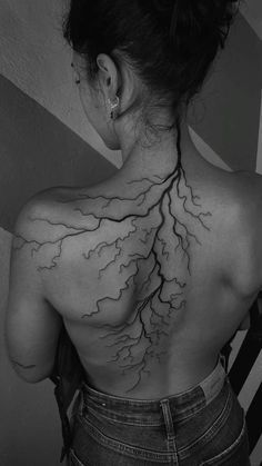 the back of a woman's neck with lightning tattoo on her upper and lower back