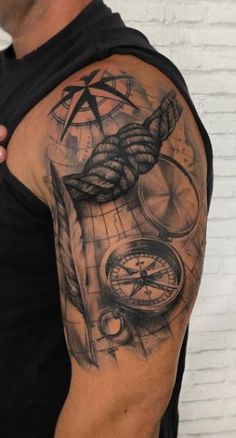 a man with a black and grey tattoo on his arm, holding onto a compass