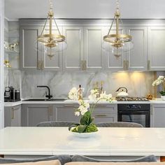 a large kitchen with white counter tops and gold chandelier hanging from the ceiling