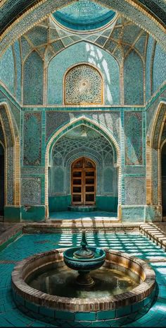 the inside of an ornate building with a fountain in the center and blue tiles on the walls