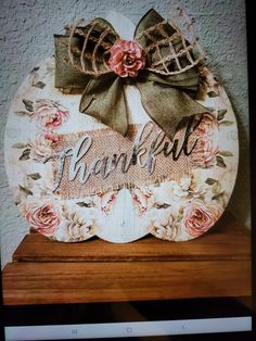 a wooden sign that says thank with flowers and bows on the front, sitting on top of a shelf