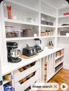 a kitchen with white shelves filled with appliances