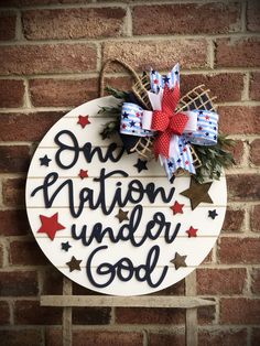 a sign that says one nation under god on the side of a brick wall with red, white and blue bows