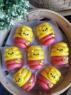 six yellow and red candies with faces on them in a basket next to a potted plant