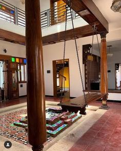 a living room filled with furniture and lots of wood hanging from the ceiling over a tiled floor