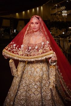 a woman in a gold and red bridal gown with a veil on her head