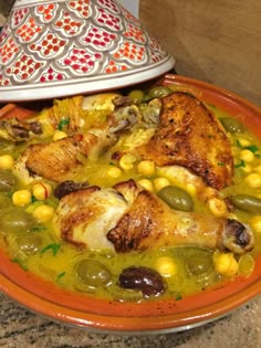 a bowl filled with chicken and vegetables on top of a table next to a lamp