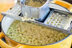 a pan filled with macaroni and cheese on top of a stove next to a strainer