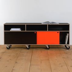 an orange and black entertainment center with wheels on the floor in front of a white wall