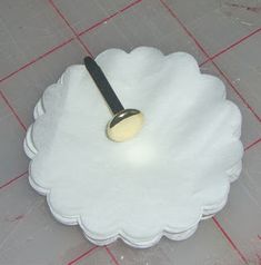 a white paper plate with a black handle on the floor next to a red and white checkered tablecloth