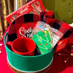 a christmas gift basket with cookies, candy and other holiday treats on a red table