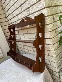 a wooden shelf with hearts on it sitting against a brick wall