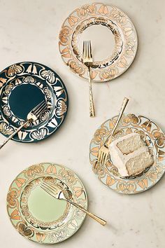 three plates with gold and green designs on them, one has a piece of cake