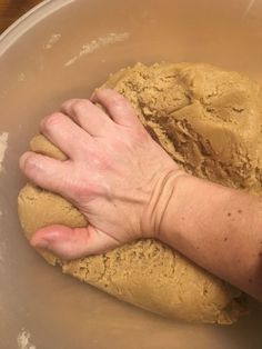 a person is kneading dough into a bowl