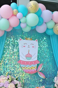 a birthday party with balloons, streamers and a cat cake on the front wall