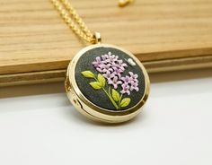 A unique and sentimental locket necklace. This floral pendant encapsulates moments with personal photos or a heartfelt message, creating a lasting keepsake to be treasured. Crafted with meticulous attention to detail, each necklace is a labor of love, sculpted by hand using small pieces of clay meticulously shaped and added one by one.  Choose between a gold or silver metal base to complement your style. For alternative designs, explore our diverse options at: https://etsy.me/2GmH7qe 🍃HOW TO ORDER / PERSONALIZATION Upon purchasing this listing, our artist will reach out to you via Etsy message to discuss the customization options, whether it be sending personal photos or specifying a special message. Additionally, you have the option to include two photos and a brief text (2-3 words) on t Keepsake Flower Charm Locket Necklace, Round Pendant Locket Necklace With Birth Flower For Anniversary, Anniversary Locket Necklace With Birth Flower, Anniversary Birth Flower Locket Necklace, Anniversary Round Pendant Locket Necklace With Birth Flower, Mother's Day Flower Pendant Locket Necklace Gift, Birth Flower Locket Necklace Keepsake, Birth Flower Locket Necklace Gift, Mother's Day Keepsake Round Pendant Locket Necklace