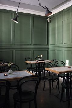 an empty restaurant with green walls and wooden tables