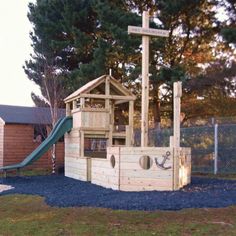 a wooden play structure with a slide and climbing frame in the middle of a yard