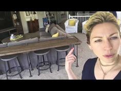 a woman pointing at the camera in front of a living room with bar stools