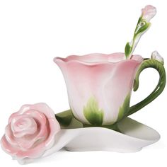 two pink roses sitting on top of a white saucer and cup with green stems