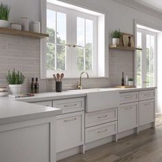 a large kitchen with white cabinets and wooden floors is pictured in this image, there are plants on the windows