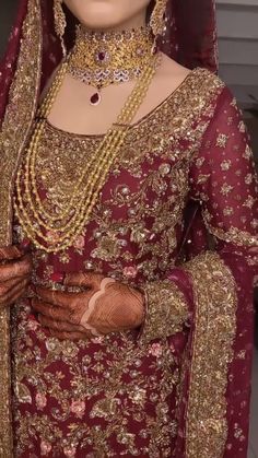 a woman in a red and gold bridal outfit with jewelry on her head,