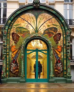 a man standing in front of an ornate doorway with butterflies painted on the doors and windows