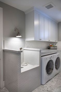 a washer and dryer in a room with white cupboards on the wall