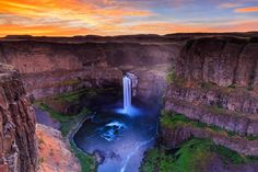 an aerial view of a waterfall in the middle of a canyon with water flowing from it