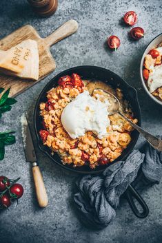 a skillet filled with food on top of a table next to other utensils