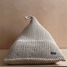 a white knitted beanie hat sitting on top of a wooden table next to a wall