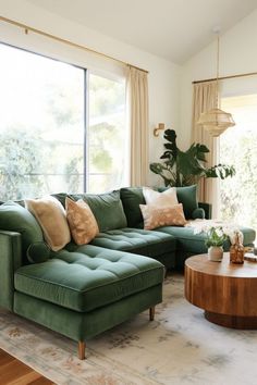 a living room filled with green couches and pillows on top of a wooden coffee table