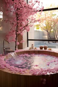 a hot tub filled with lots of pink flowers next to a tree in front of a window